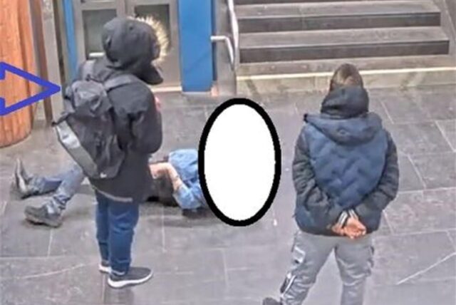 Mehrere Männer stehen um einen am Boden liegenden Mann herum. Das Gesicht des letzteren ist unkenntlich gemacht. Aufnahme von der Haltestelle Brunnenstraße in Dortmund.