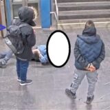 Mehrere Männer stehen um einen am Boden liegenden Mann herum. Das Gesicht des letzteren ist unkenntlich gemacht. Aufnahme von der Haltestelle Brunnenstraße in Dortmund.