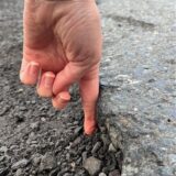 Jana Zander hält ihren linken Zeigefinger in das Schlagloch auf dem Altstadtring, das ihren Reifen beschädigte.