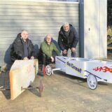 Menschen stehen mit Seifenkisten vor einer Garage in Waltrop.