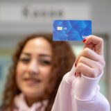 Eine junge Frau hält eine Bezahlkarte für Geflüchtete in die Kamera.