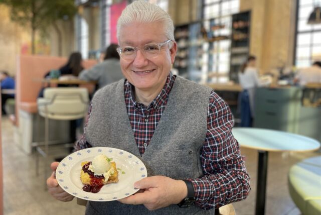 Ein Gast im Café ButterRaum in Dortmund-Huckarde hält einen Teller mit einer Waffel in die Kamera.