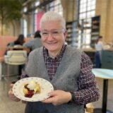 Ein Gast im Café ButterRaum in Dortmund-Huckarde hält einen Teller mit einer Waffel in die Kamera.
