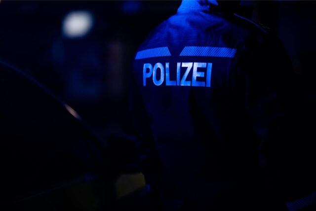 Ein Polizist steht neben einem Polizeiauto