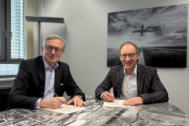 Ludger van Bebber und Ulrich Jaeger sitzen an einem Tisch und unterschreiben einen Gesellschaftervertrag für den Flughafen Dortmund.