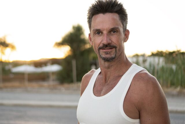 Mark Lewandowski – Teilnehmer bei GNTM 2025 – steht im Tanktop vor der Kamera und lächelt leicht.