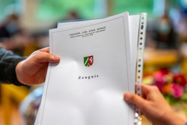 Eine Lehrerin übergibt ein Zeugnis einer Schule in NRW an einen Schüler.