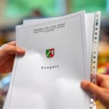 Eine Lehrerin übergibt ein Zeugnis einer Schule in NRW an einen Schüler.