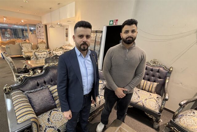 Ibrahim Assani Sharbawi und Munzer Safaya vor einem Sofa in ihrem Ladenlokal.