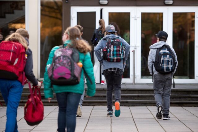 Schülerinnen und Schüler gehen in Eingang des Schulgebäudes