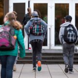 Schülerinnen und Schüler gehen in Eingang des Schulgebäudes