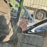 Das Lenkrad eines Busses ist zu sehen, davor die Hand des Fahrers mit einer Zigarette darin.