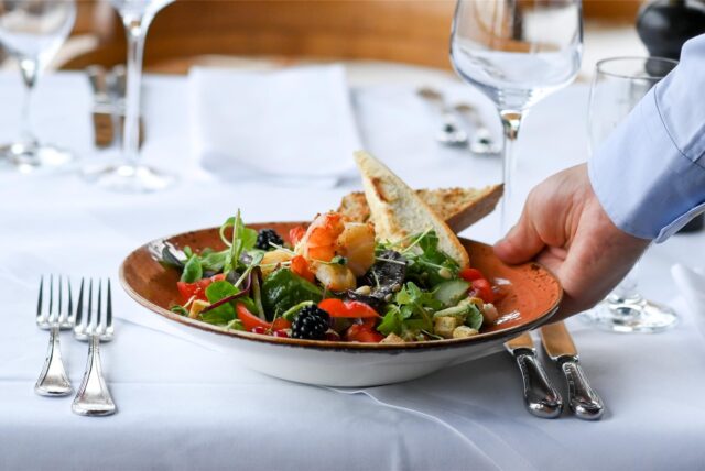 Kellner serviert einen Salatteller auf einer festlichen Tafel.