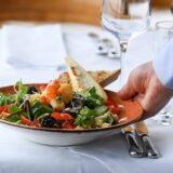 Kellner serviert einen Salatteller auf einer festlichen Tafel.