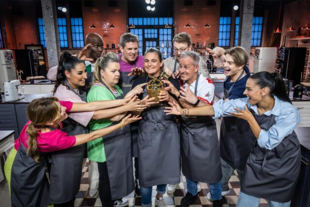 Ella Endlich, Senna Gammour, Manuela Wisbeck, Steffen Groth, Nadine Angerer, Bruce Darnell, Maxi Gstettenbauer, Pierre Littbarski, Vincent Gross, Amira Aly, die Teilnehmer von „Das große Promibacken 2025“, blicken auf den goldenen Cupcake, den der Gewinner mit nach Hause nimmt.