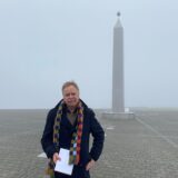 Volker Lindner im dunklen Mantel mit buntem Schal am Sonnenuhr-Obelisken auf der Halde Hoheward in Herten.