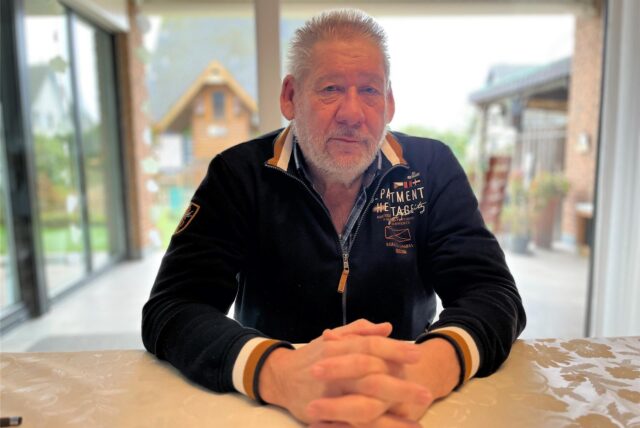 Erich Stollbrink sitzt an seinem Wohnzimmertisch.