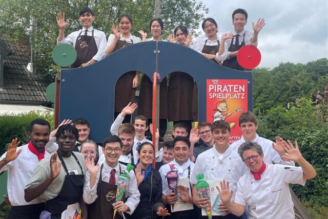 Sie kommen aus aller Welt und lernen für die ganze Welt: Küchenchefin Bianca Overkamp (unten rechts) mit internationalen Azubis und Mitarbeitern. Wer in der Gastronomie lernt, kann überall in der Welt einen Job finden – sagt Günther Overkamp und erklärt auch, warum.