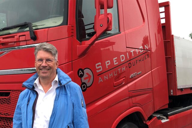 Spediteur Horst Anhuth steht vor seinem roten Lkw.