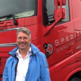Spediteur Horst Anhuth steht vor seinem roten Lkw.