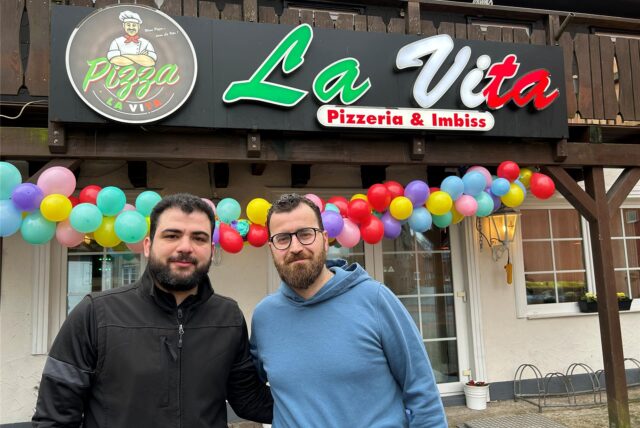 Zwei Männer stehen vor der Pizzeria.