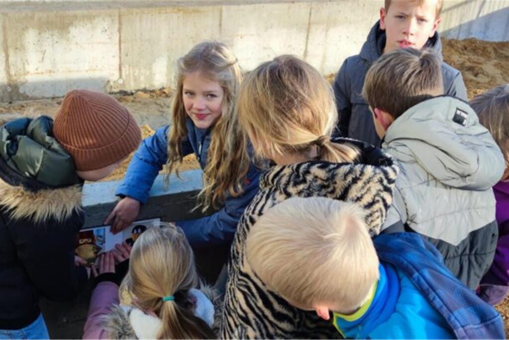 Sieben Grundschulkinder kleben ein Bild auf einen Betonblock auf einer Baustelle Sieben Grundschulkinder kleben ein Bild auf einen Betonblock auf einer Baustelle