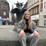 Eine junge Frau, die an einem Brunnen sitzt.
