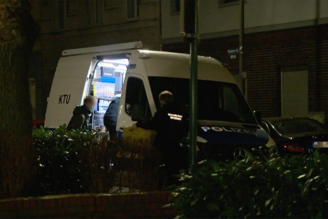 Polizeibeamte der Kriminaltechnischen Untersuchungsstelle stehen an einem Einsatzfahrzeug.