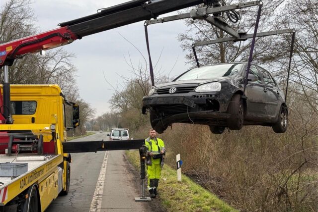 Ein Kran des ADAC hebt ein kaputtes Auto aus einem Straßengraben