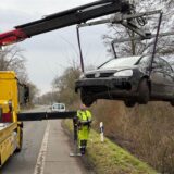 Ein Kran des ADAC hebt ein kaputtes Auto aus einem Straßengraben