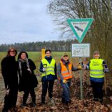 Sechs Menschen mit Warnwesten vom Naturschutzbund stehen mit Schaufeln an einem Waldrand.