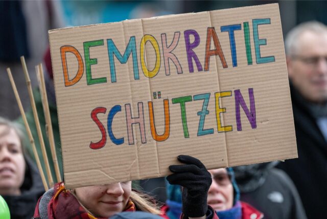 Auf einem Plakat steht „Demokratie schützen“