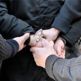 Polizisten legen einem Mann Handschellen an.