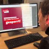 Ein Mann schaut auf einen Computer-Bildschirm, auf dem der Hinweis steht: „Die Linke Dortmund gesperrt!“