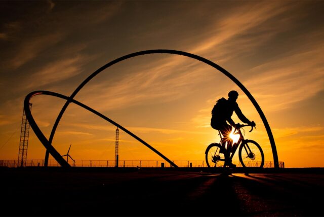 Ein Radfahrer vor dem Hintergrund des Sonnenuntergangs am Horizont-Observatorium.