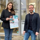 Bürgermeister Marcel Mittelbach und Christina Rode mit einem Plakat der Assistenzhunde-Kampagne vor dem Haupteingang zum Rathaus-Altbau.