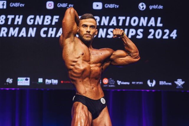 Tom Kutschinski steht bei einem Wettkampf auf der Bühne und nimmt eine Bodybuilder-Pose ein.