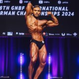 Tom Kutschinski steht bei einem Wettkampf auf der Bühne und nimmt eine Bodybuilder-Pose ein.