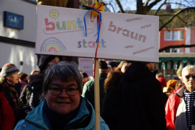 Eine Frau hält ein Plakat mit der Aufschrift „bunt statt braun“