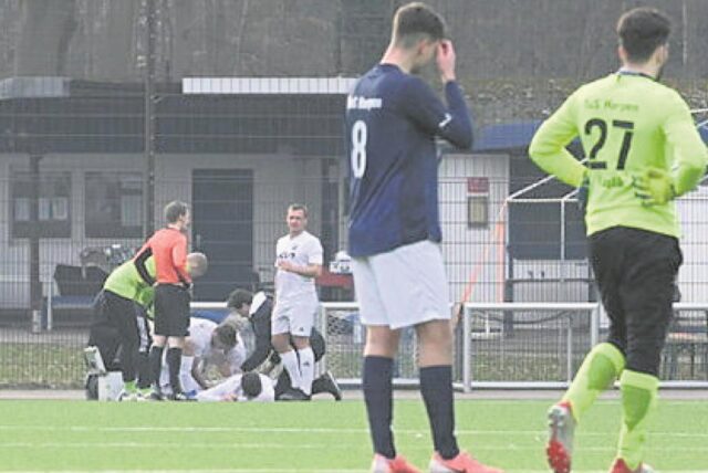 Die Spieler des TuS Harpen genehmigen sich eine Verschnaufpause während im Hintergrund Timo Schmidt behandelt wird.