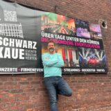 Andreas Weidner vor einem Plakat.