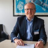 Wolfgang Mueller sitzt am Schreibtisch.