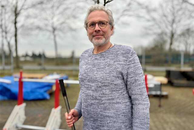 Christian Barz stellt mit seinem Unternehmen Herne Protect Trucksperren her. Im Hintergrund steht eine rot-weiße Trucksperre, die aus zusammengebauten Metallteilen besteht.