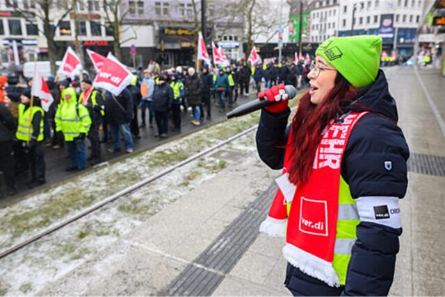 Mitarbeiter der hannoverschen Verkehrsbetrieben „Üstra“ laufen während eines Warnstreiks an einer Haltestelle vorbei.