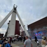 Weißer Riese auf dem Zechengelände Schlägel & Eisen in Herten, davor tanzen Besucher vor einer Bühne.
