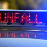Die Anzeige auf einem Polizeiwagen leuchtet und zeigt das Wort „Unfall“.