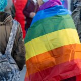 Eine Demonstrantin hat eine Regenbogenflagge über die Schultern gelegt.