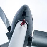 Ein Höhenretter der Feuerwehr schwebt, an Seilen sichert, beim Einsatztraining am Windrad auf der Hertener Halde Hoppenbruch direkt unter der Turbine.