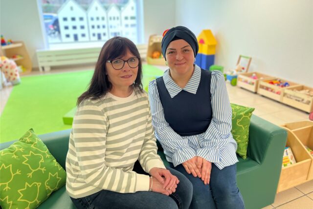 Andrea Weiß und Sedef Külcü sitzen auf einem grünen Kindersofa.