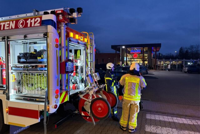 Feuerwehrkräfte stehen an ihrem Einsatzfahrzeug.